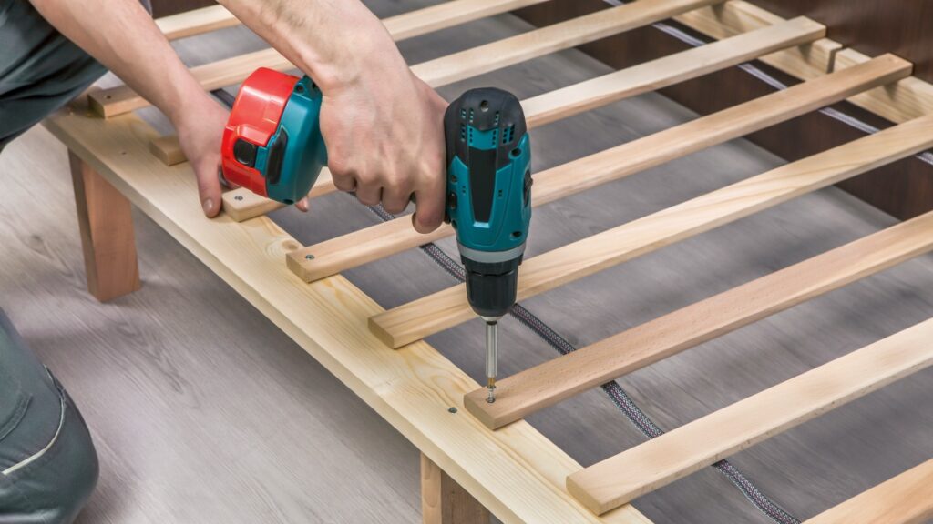 Wooden furniture assembling- woodworker screwing screws using a cordless